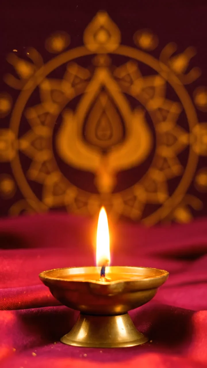 Vedic muhurtham invitation film โ a diya glowing on red and gold velvet